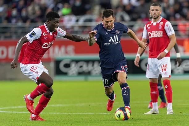 Marshall Munetsi of Reims competes with Lionel Messi of PSG during the Ligue 1 Uber Eats match between Reims and Paris Saint Germain at Stade Auguste...