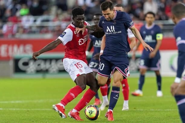 Marshall Munetsi of Reims competes with Lionel Messi of PSG during the Ligue 1 Uber Eats match between Reims and Paris Saint Germain at Stade Auguste...