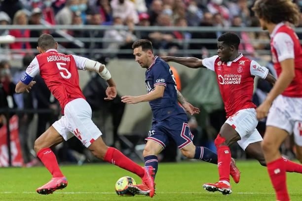 Lionel Messi of PSG is challenged by Yunis Abdelhamid and Marshall Munetsi of Reims during the Ligue 1 Uber Eats match between Reims and Paris Saint...