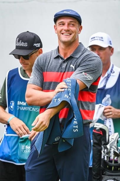 Bryson DeChambeau smiles as he uses a towel to wipe sweat off on the first tee during the final round of the BMW Championship, the second event of...