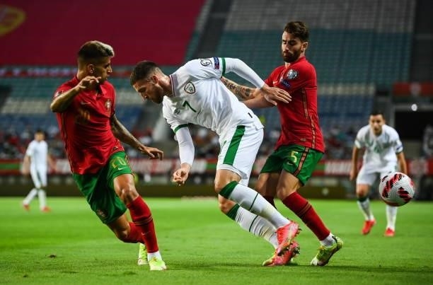 Faro , Portugal - 1 September 2021; Matt Doherty of Republic of Ireland in action against João Cancelo, left, and Raphael Guerreiro of Portugal...