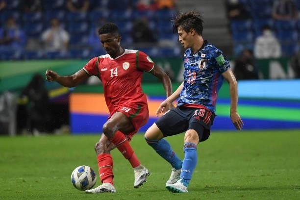 Amjad Al Harthi of Oman keeps the ball under the pressure from Kyogo Furuhashi of Japan during the FIFA World Cup Asian Qualifier Final Round Group B...