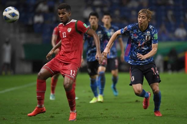 Junya Ito of Japan and Abdulaah Fawaz of Oman compete for the ball during FIFA World Cup Asian Qualifier Final Round Group B match between Japan and...