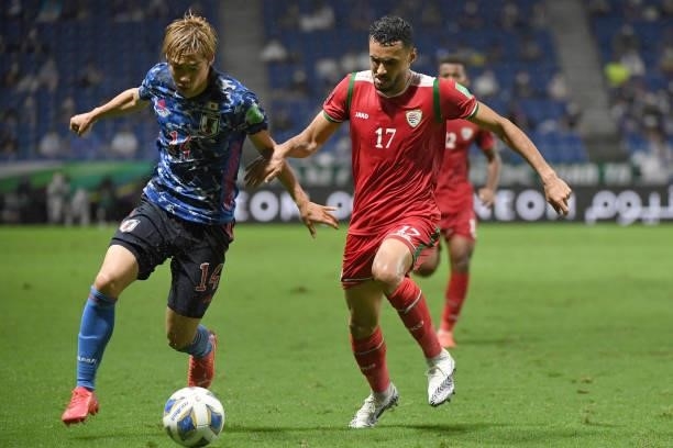 Junya Ito of Japan dribbles the ball under the puressure from Ali Sulaiman Al Busaidi of Oman during FIFA World Cup Asian Qualifier Final Round Group...