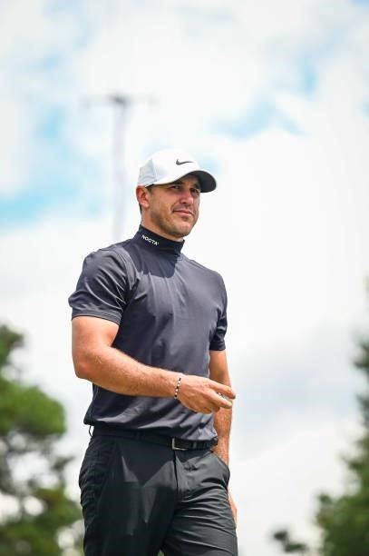 Brooks Koepka, wearing a Nike NOCTA turtleneck, smiles as he walks off the third hole green during the first round of the TOUR Championship, the...