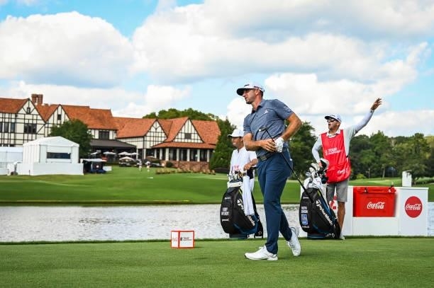 Dustin Johnson plays his shot from the 16th tee as his caddie Austin Johnson gestures fore left during the first round of the TOUR Championship, the...