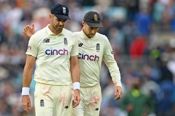 England's captain Joe Root and England's James Anderson walk off as players leave the field due to bad light during play on the third day of the...