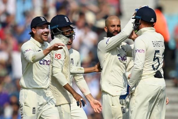 England's Moeen Ali celebrates with teammates after taking the wicket of India's captain Virat Kohli during play on the fourth day of the fourth...