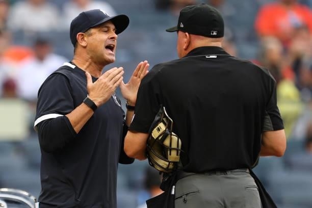 Manager Aaron Boone of the New York Yankees argues with home plate umpire Jeff Nelson after making a pitching change against the Baltimore Orioles in...