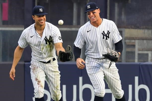 Right fielder Giancarlo Stanton of the New York Yankees flips the ball with Aaron Judge after making a diving catch on a ball hit by Anthony...