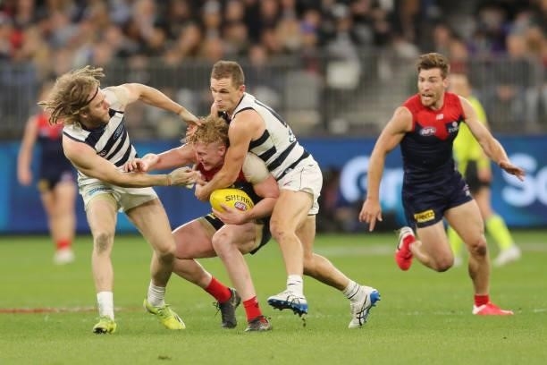 Clayton Oliver of the Demons is tackled by Cameron Guthrie and Joel Selwood of the Cats during the 2021 AFL First Preliminary Final match between the...