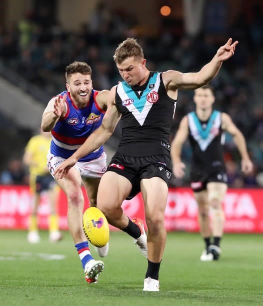 Ollie Wines of the Power kicks the ball away from Marcus Bontempelli of the Bulldogs during the 2021 AFL Second Preliminary Final match between the...