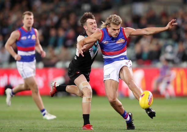 Bailey Smith of the Bulldogs kicks the ball with Zak Butters of the Power chasing during the 2021 AFL Second Preliminary Final match between the Port...
