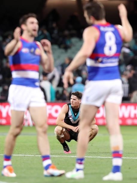 Connor Rozee of the Power slumps to the ground as the Bulldogs celebrate the win during the 2021 AFL Second Preliminary Final match between the Port...