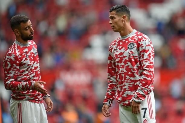 Manchester United's Portuguese midfielder Bruno Fernandes speaks with Manchester United's Portuguese striker Cristiano Ronaldo as they warm up ahead...