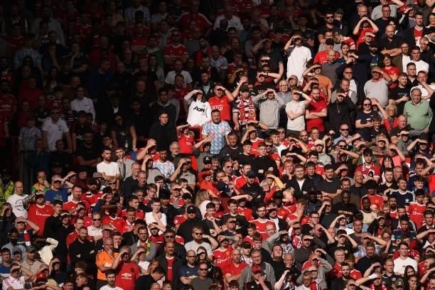 United fans shield their eyes from the sun during the English Premier League football match between Manchester United and Newcastle at Old Trafford...