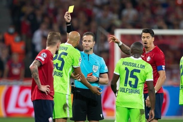Referee Danny Makkelie shows John Anthony Brooks of VfL Wolfsburg the yellow card during the UEFA Champions League group G match between Lille OSC...