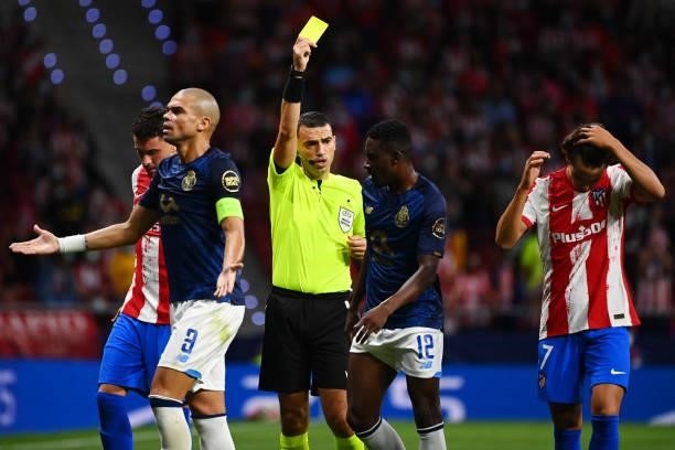 Romanian referee Ovidiu Hategan presents a yellow card to FC Porto's Nigerian defender Zaidu Sanusi during the UEFA Champions League first round...