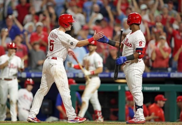 Andrew Knapp of the Philadelphia Phillies celebrates with teammate Jean Segura after scoring the winning run on a passed ball in the ninth inning...