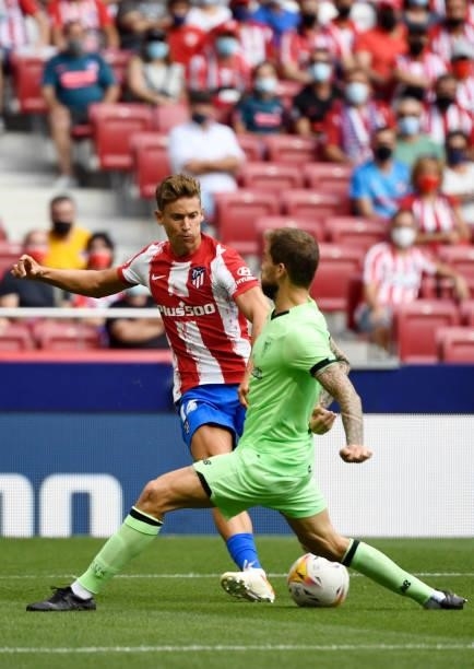 Atletico Madrid's Spanish midfielder Marcos Llorente is challenged by Athletic Bilbao's Spanish defender Inigo Martinez during the Spanish League...