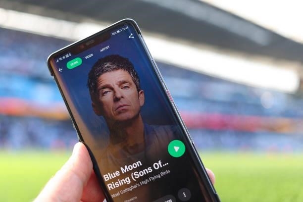 Mobile telephone with the Spotify app on listening to Blue Moon Rising by Manchester City fan Noel Gallagher and his band the High Flying Birds at...