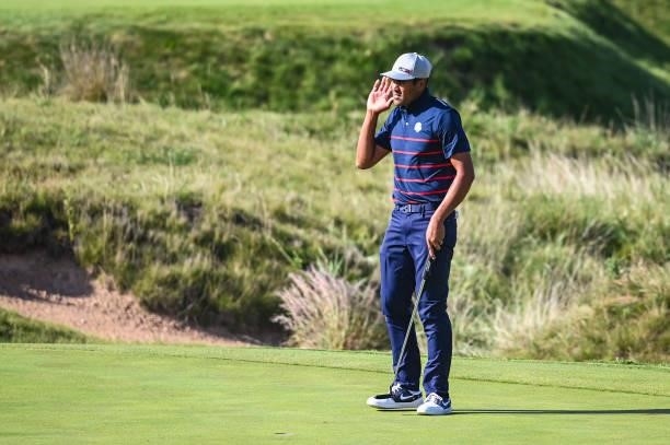 Tony Finau of the U.S. Team celebrates and puts his hand to his ear to get fans to cheer after making a birdie putt on the ninth hole green during...