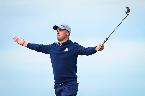Justin Thomas raises his arms and putter as he celebrates making an eagle putt on the 16th hole green during Friday Afternoon Four-ball Matches of...