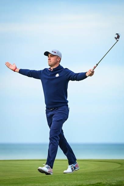 Justin Thomas raises his arms and putter as he celebrates making an eagle putt on the 16th hole green during Friday Afternoon Four-ball Matches of...