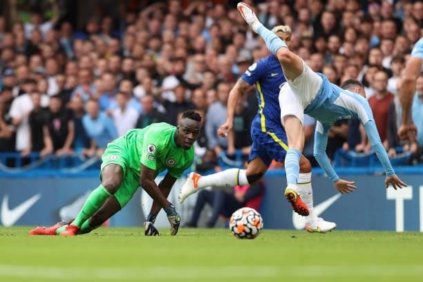 Chelsea goalkeeper Edouard Mendy keeps his eye on the ball as Phil Foden of Man City goes flying over him during the Premier League match between...