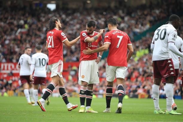 Bruno Fernandes of Manchester United is consoled by teammates Edinson Cavani of Manchester United and Cristiano Ronaldo of Manchester United after...
