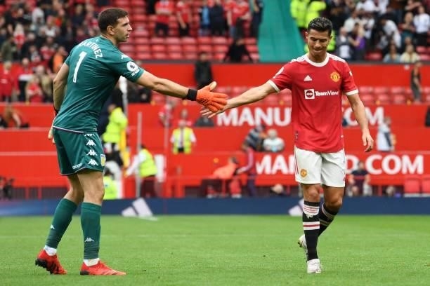 Aston Villa's Argentinian goalkeeper Emiliano Martinez taps hands with Manchester United's Portuguese striker Cristiano Ronaldo after the English...