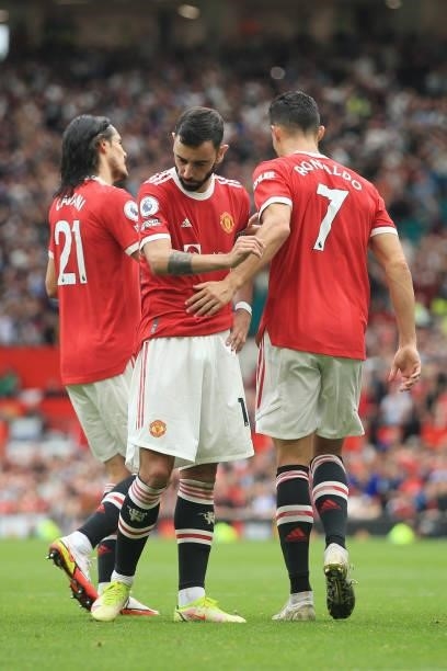 Bruno Fernandes of Manchester United is consoled by teammates Edinson Cavani of Manchester United and Cristiano Ronaldo of Manchester United after...