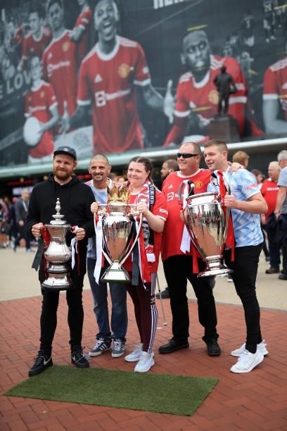 Manchester United fans pose with replica versions of the FA Cup , Premier League and UEFA Champions League trophies before the Premier League match...