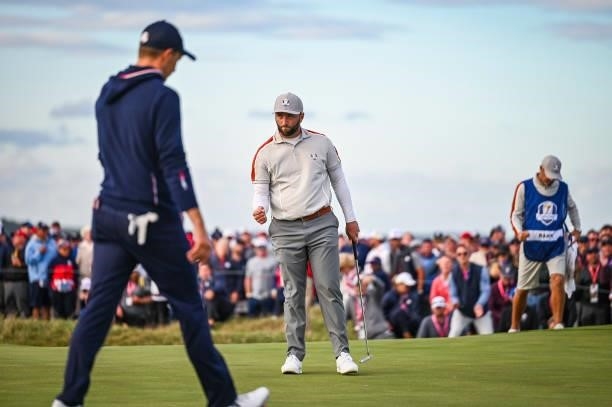 Jon Rahm of Spain and Team Europe celebrates with a fist pump after making a putt on the 15th hole green as Jordan Spieth of the U.S. Team walks by...