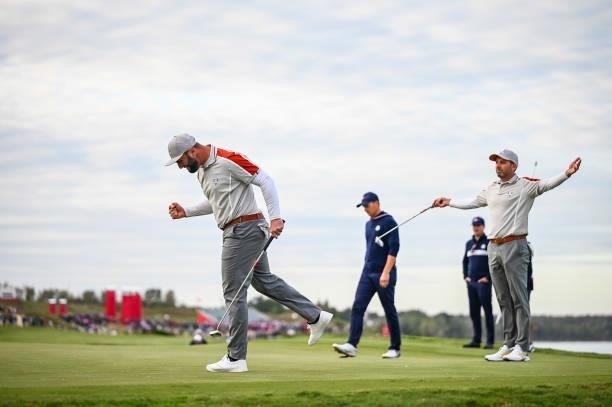 Jon Rahm of Spain and Team Europe pumps his fist after making an eagle putt on the 16th hole green as teammate Sergio Garcia celebrates with arms...
