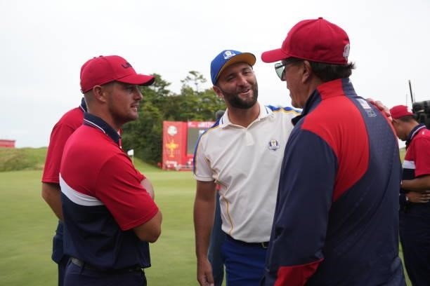 Jon Rahm of Spain and Team Europe visits with United States members Bryson DeChambeau, Scottie Scheffler and United States Vice-Captain Phil...