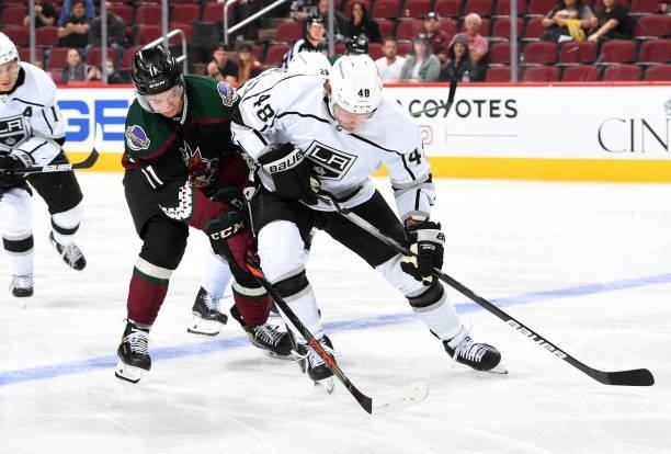 Brendan Lemieux of the Los Angeles Kings skates with the puck while being defended by Dylan Guenther of the Arizona Coyotes at Gila River Arena on...