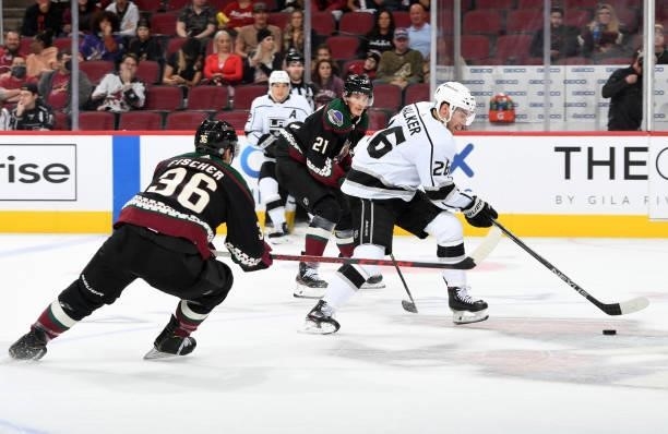 Sean Walker of the Los Angeles Kings skates the puck past Loui Eriksson and Christian Fischer of the Arizona Coyotes at Gila River Arena on September...