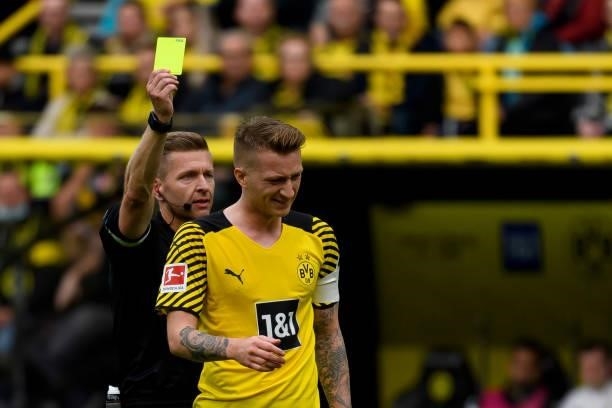 Referee Tobias Welz shows Marco Reus of Borussia Dortmund the yellow card during the Bundesliga match between Borussia Dortmund and FC Augsburg at...