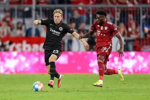 Jens Petter Hauge of Eintracht Frankfurt and Alphonso Davies of Bayern Muenchen battle for the ball during the Bundesliga match between FC Bayern...