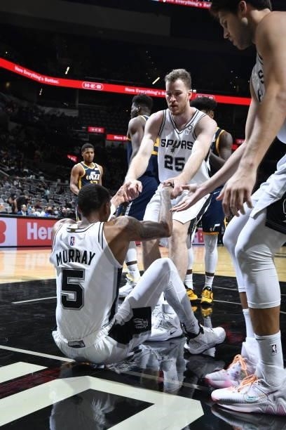 Jakob Poeltl of the San Antonio Spurs helps up his teammate during the game against the Utah Jazz during a pre-season game on October 4, 2021 at the...