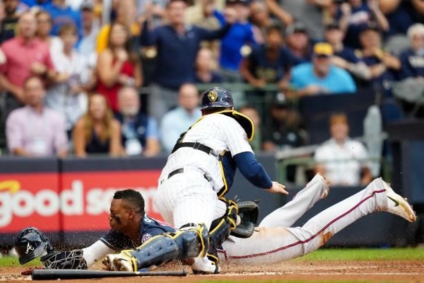 Jorge Soler of the Atlanta Braves slides safely into home to score a run as Manny Piña of the Milwaukee Brewers applies the tag in the third inning...