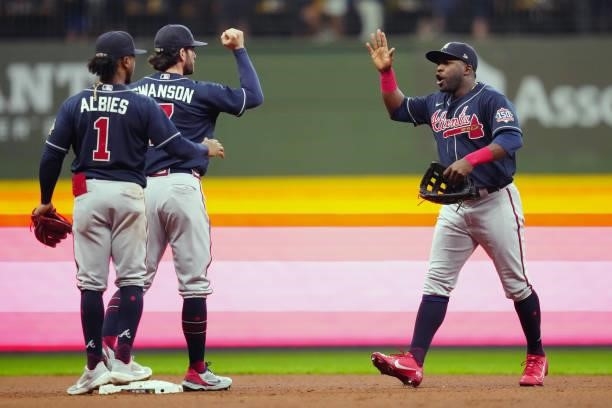 Guillermo Heredia of the Atlanta Braves celebrates with teammates Ozzie Albies and Dansby Swanson after the Braves defeated the Milwaukee Brewers 3-0...