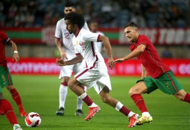 Akram Afif of Qatar competes for the ball with Diogo Dalot of Portugal ,during the international friendly match between Portugal and Qatar at Estadio...