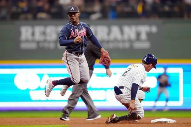 Luis Urías of the Milwaukee Brewers slides into second base while Ozzie Albies of the Atlanta Braves throws to first base for the double play in the...