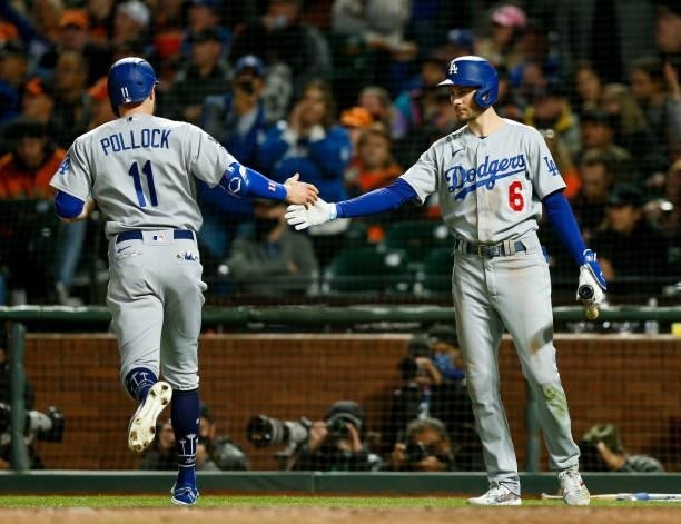 Pollock of the Los Angeles Dodgers hi fives Trea Turner after scoring in the eight inning during Game 2 of the NLDS between the Los Angeles Dodgers...
