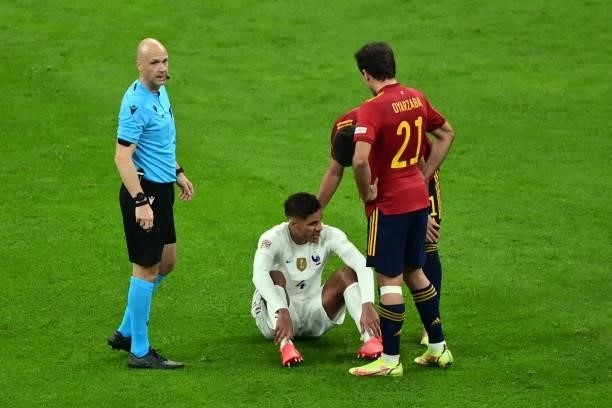 France's defender Raphael Varane reacts next to British goalkeeper Anthony Taylor after getting injured during the Nations League final football...