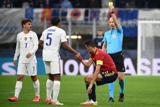 France's defender Jules Kounde is shown a yellow card by British goalkeeper Anthony Taylor for a foul on Spain's midfielder Sergio Busquets during...