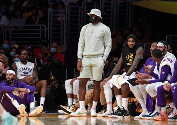LeBron James of the Los Angeles Lakers, in civilian clothes, follows the game from the bench during the second half of preseason game against Phoenix...