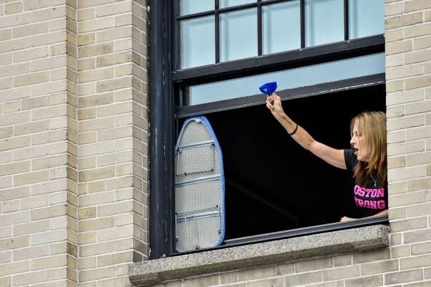 Woman cheers on runners from a high rise building during the 125th Boston Marathon in Boston, Massachusetts on October 11, 2021.
